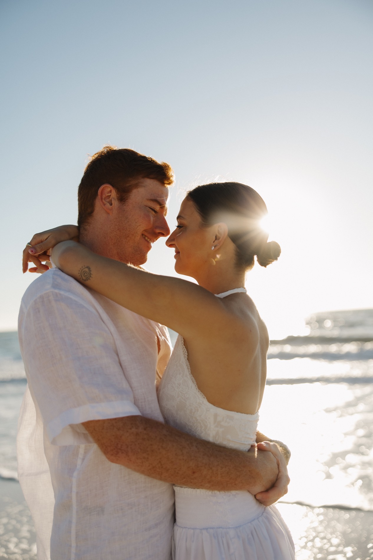 Jacquelyn and Ryan embracing by the ocean