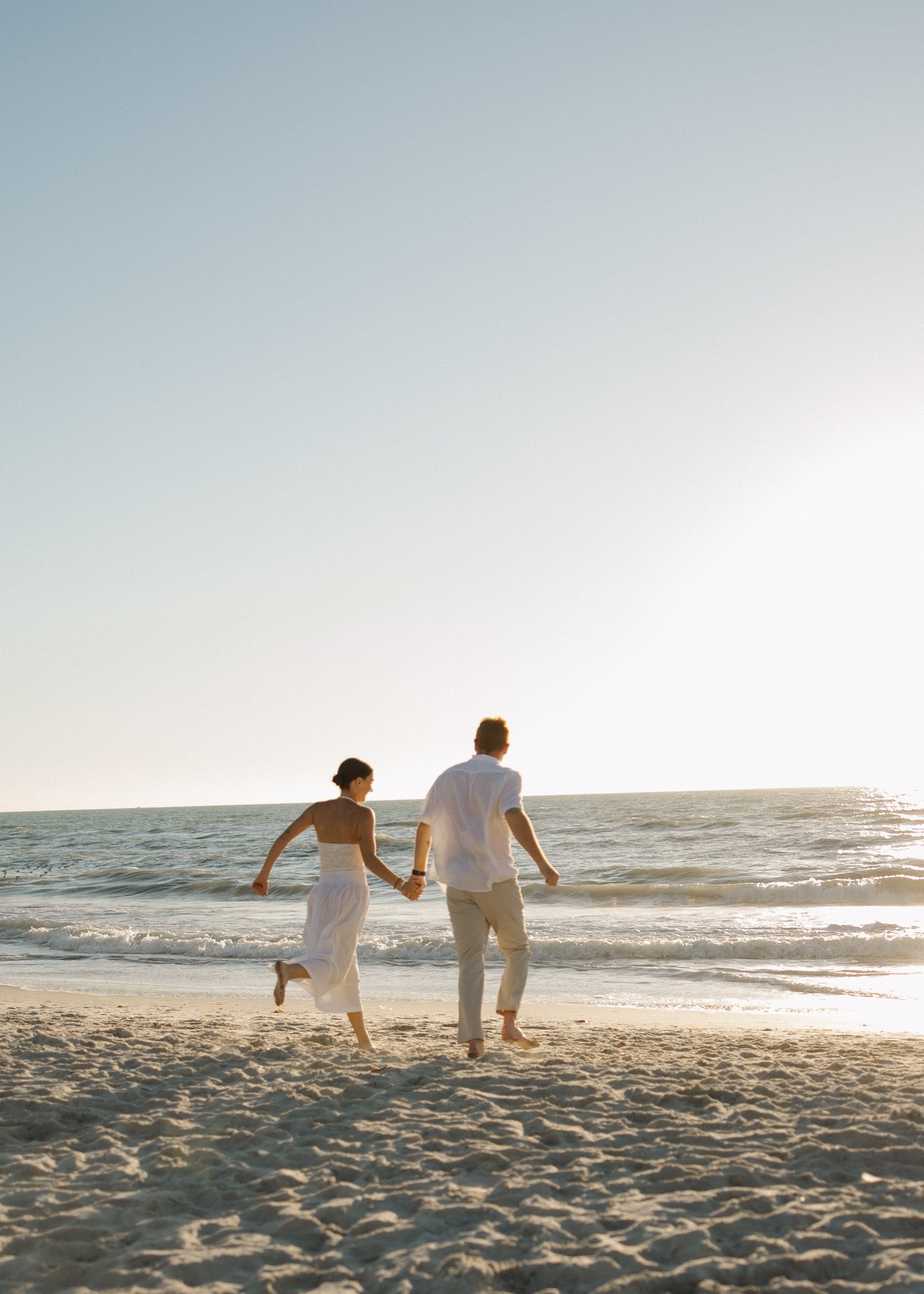Jacquelyn and Ryan running hand in hand toward the ocean