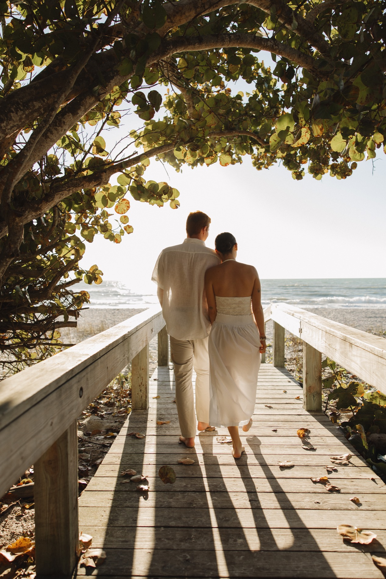 Jacquelyn and Ryan walking together on a boardwalk by the beach